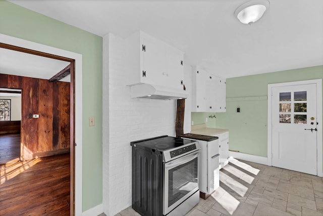 kitchen featuring custom exhaust hood, white cabinets, stainless steel electric range, and baseboards