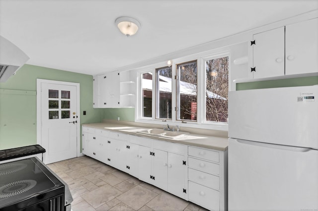 kitchen featuring light countertops, electric range, open shelves, and freestanding refrigerator