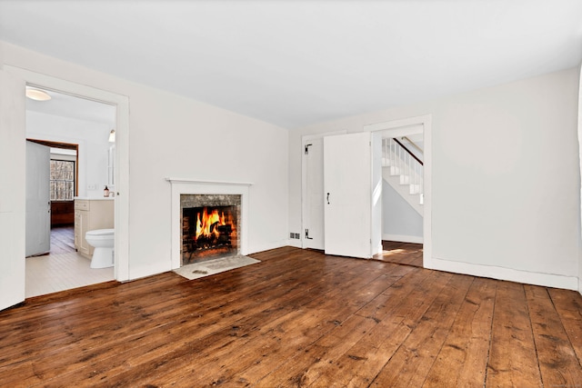 unfurnished living room with wood-type flooring and a fireplace with flush hearth