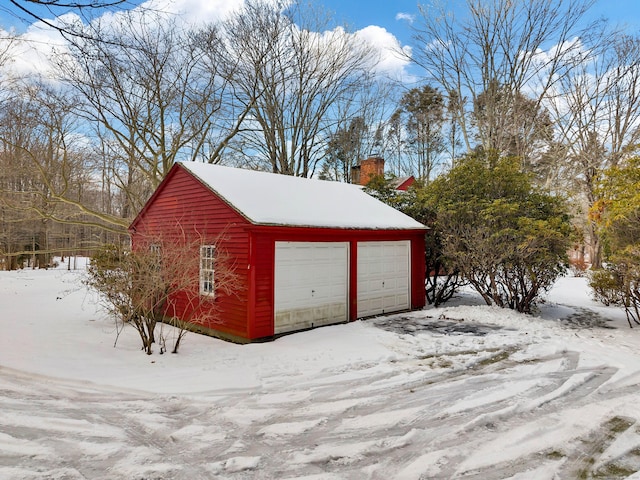 snow covered garage featuring a detached garage