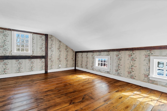 bonus room with hardwood / wood-style floors, wallpapered walls, baseboards, and vaulted ceiling