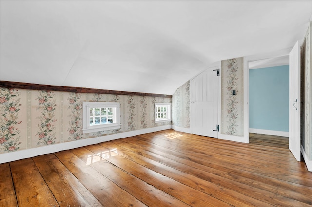 interior space with wallpapered walls, lofted ceiling, baseboards, and hardwood / wood-style floors