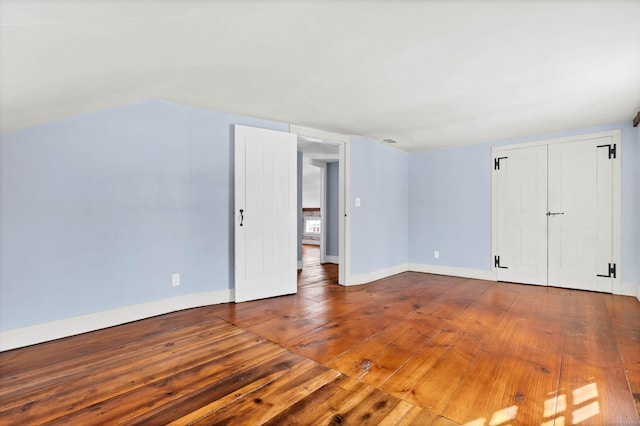 interior space with lofted ceiling, baseboards, and wood-type flooring