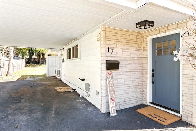 doorway to property with stone siding and fence