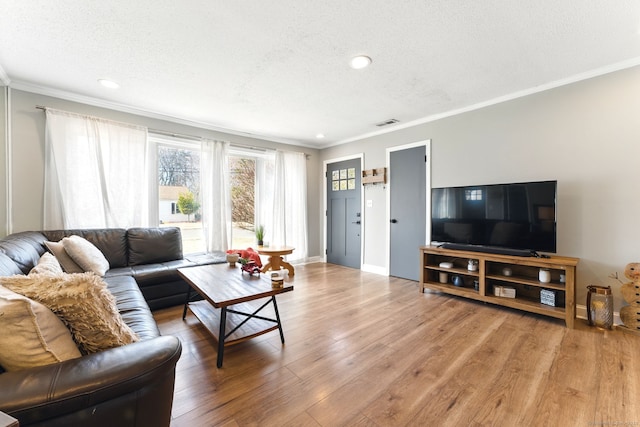 living room with a textured ceiling, wood finished floors, and ornamental molding