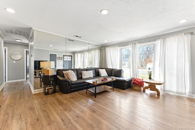 living area featuring visible vents, a textured ceiling, wood finished floors, and crown molding