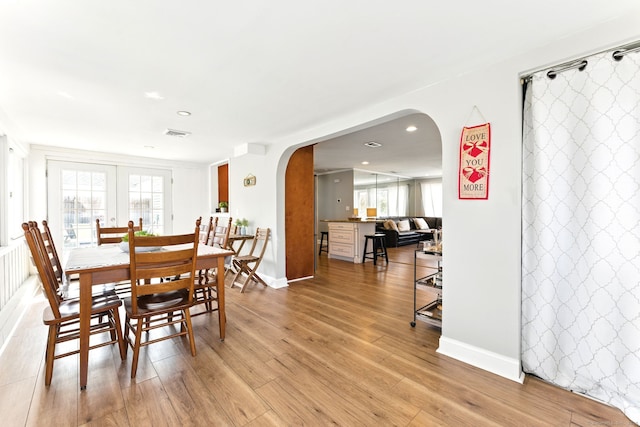 dining room featuring visible vents, baseboards, light wood-type flooring, recessed lighting, and arched walkways