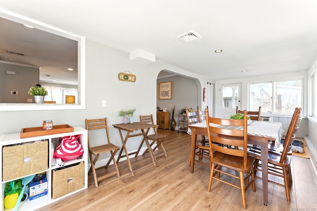 dining room with recessed lighting, arched walkways, visible vents, and light wood finished floors