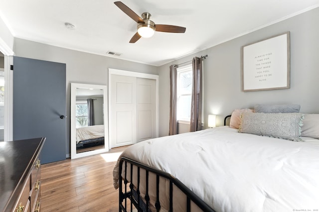 bedroom featuring visible vents, multiple windows, light wood-style floors, and a ceiling fan