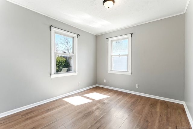 spare room featuring wood finished floors, a healthy amount of sunlight, and baseboards