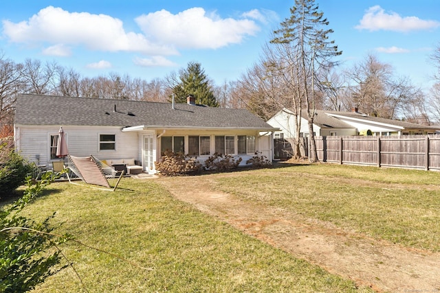 back of property with fence, a lawn, a sunroom, and roof with shingles