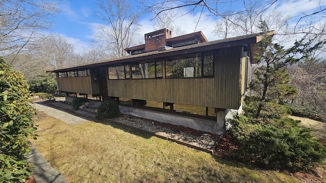 rear view of house featuring a yard and a chimney