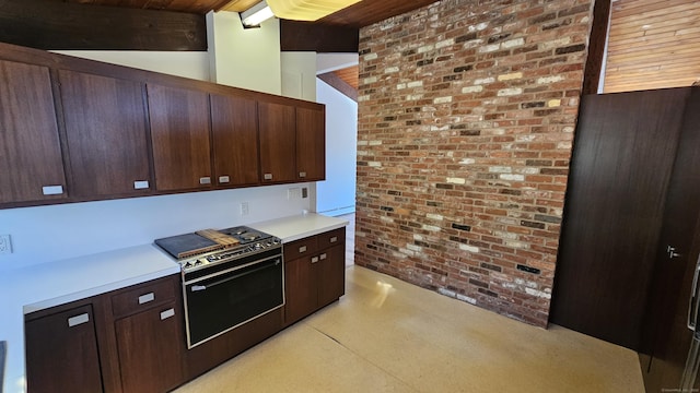 kitchen featuring dark brown cabinetry, range with electric cooktop, brick wall, and light countertops