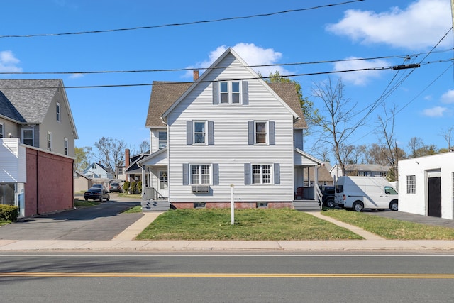 view of front of house featuring a chimney, a front lawn, and a shingled roof