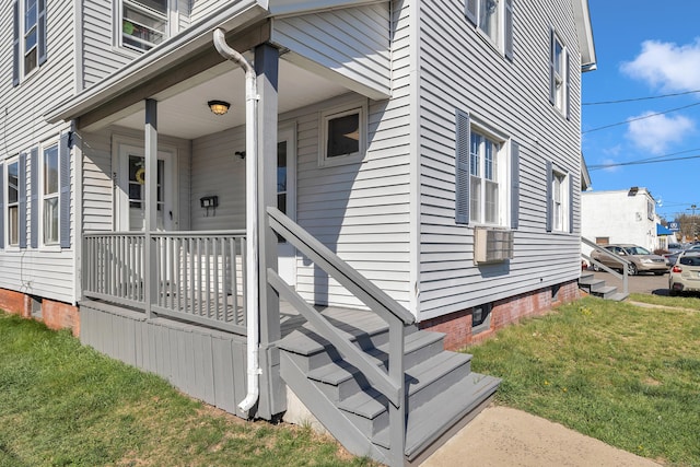 property entrance featuring crawl space, a lawn, and covered porch