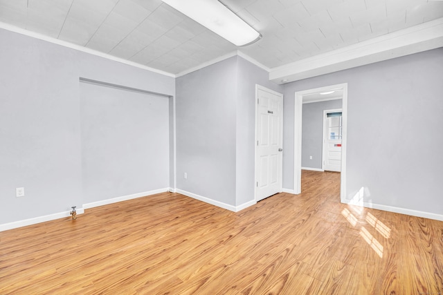 unfurnished room with baseboards, light wood-style floors, and crown molding