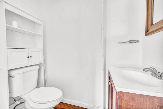 bathroom with vanity, toilet, wood finished floors, and baseboards