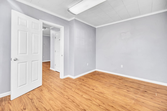 unfurnished room featuring crown molding, baseboards, and light wood-type flooring