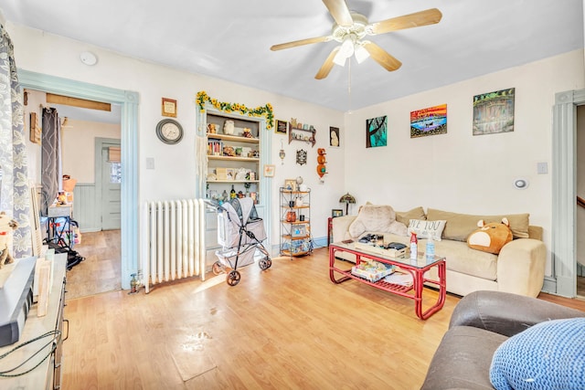 living room with light wood-type flooring, ceiling fan, and radiator heating unit