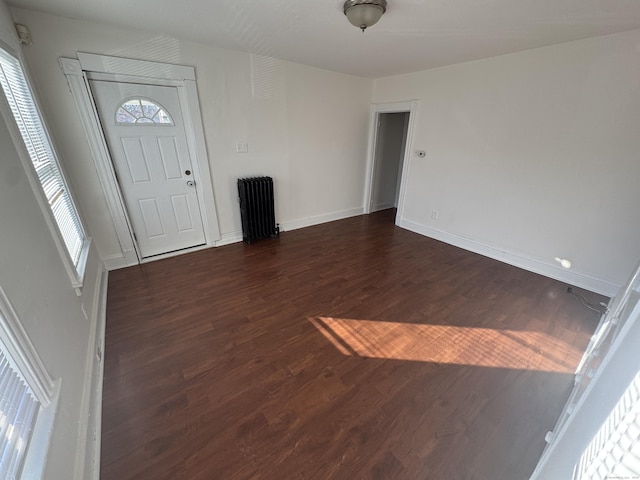 foyer with radiator, dark wood-style floors, and baseboards