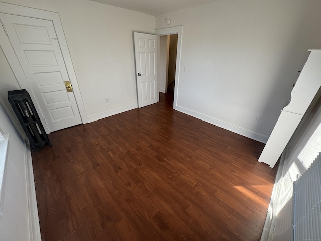 unfurnished bedroom with dark wood-type flooring and baseboards