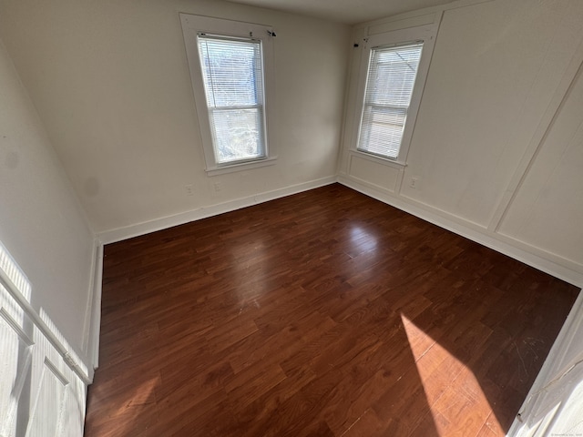 unfurnished room with baseboards and dark wood-style flooring