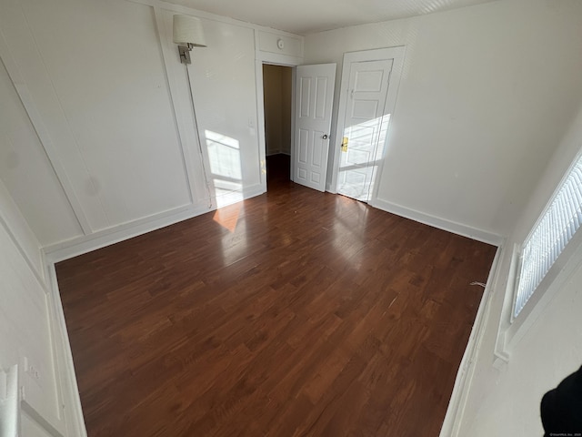 unfurnished room featuring dark wood-style floors and a decorative wall