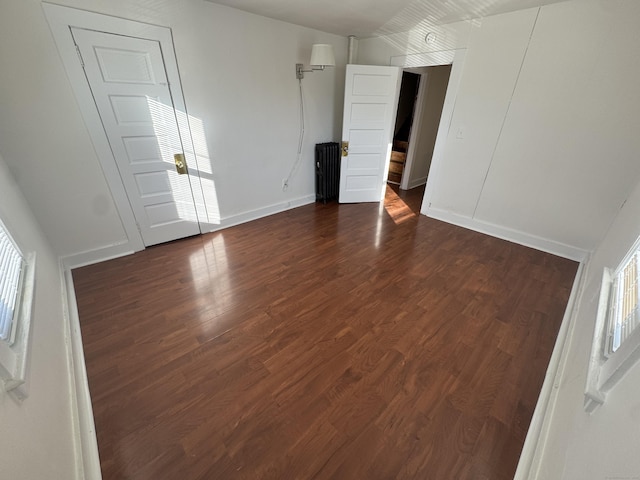 spare room featuring dark wood-type flooring and baseboards