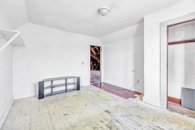 unfurnished room featuring lofted ceiling and hardwood / wood-style flooring