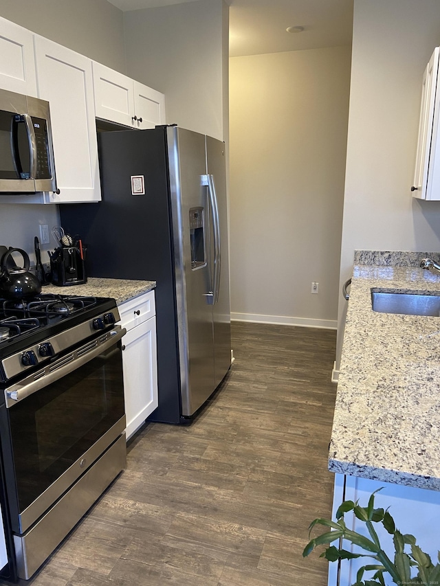 kitchen featuring dark wood-style floors, white cabinets, stainless steel appliances, and a sink