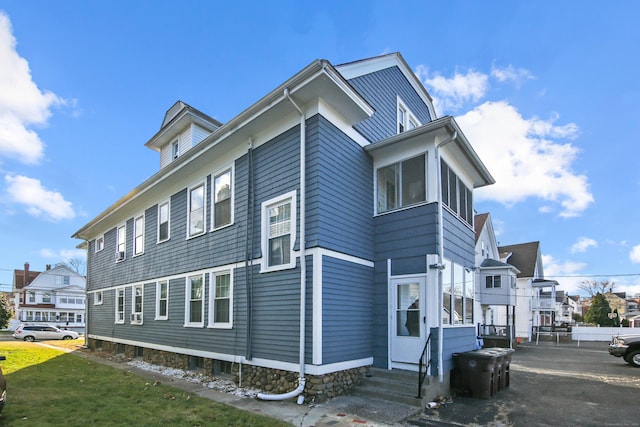 view of property exterior with a residential view, entry steps, and a yard