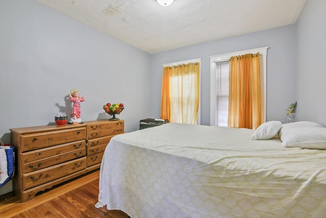 bedroom with a textured ceiling and wood finished floors