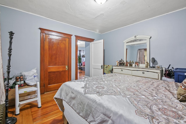 bedroom with wood finished floors and ornamental molding