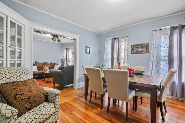 dining room with light wood-style floors, baseboards, and ornamental molding