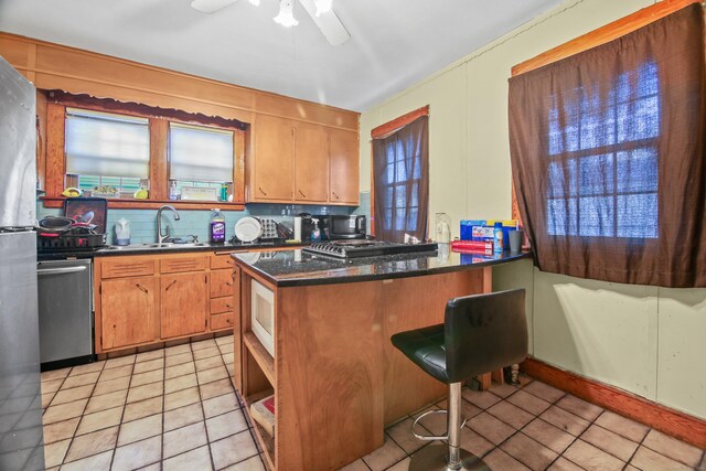 kitchen featuring a sink, a kitchen breakfast bar, dishwasher, and light tile patterned floors