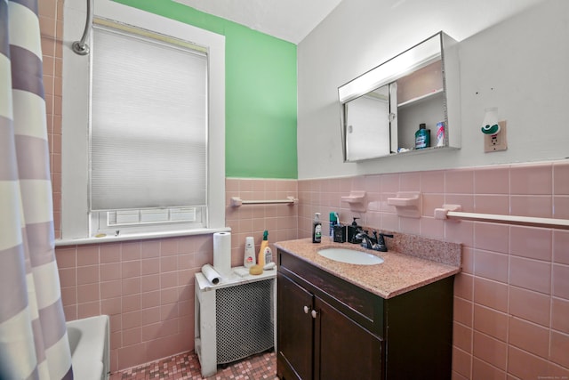 full bathroom featuring vanity, tile walls, and wainscoting