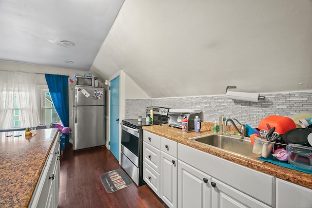 kitchen featuring dark wood finished floors, lofted ceiling, stainless steel appliances, white cabinets, and tasteful backsplash