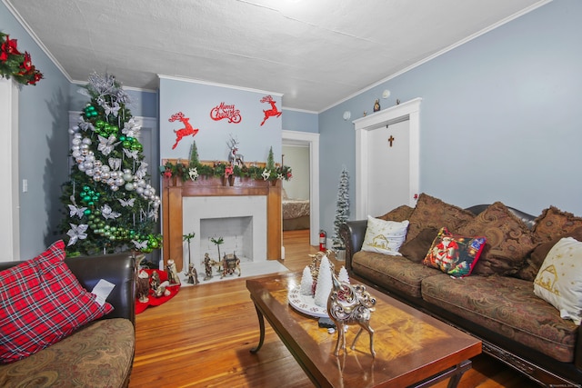 living area with a fireplace with flush hearth, wood finished floors, and ornamental molding