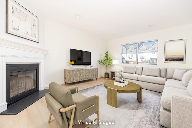 living area with a glass covered fireplace, wood finished floors, and baseboards