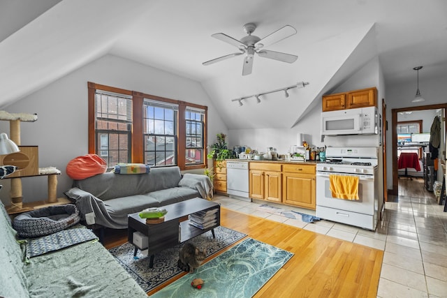 living area featuring rail lighting, vaulted ceiling, light tile patterned floors, and a ceiling fan