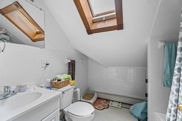 bathroom featuring toilet, vaulted ceiling with skylight, tile walls, a baseboard radiator, and vanity