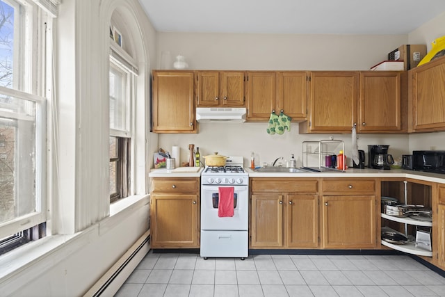 kitchen with under cabinet range hood, plenty of natural light, white gas range, and light countertops