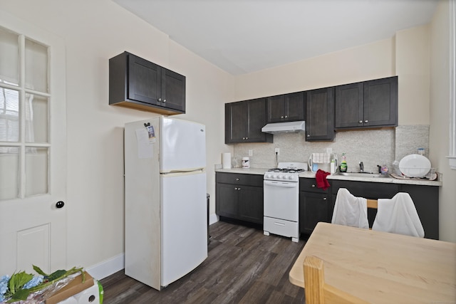 kitchen with white appliances, light countertops, dark wood-type flooring, under cabinet range hood, and tasteful backsplash