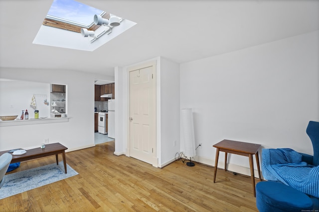 sitting room featuring light wood finished floors, a skylight, and baseboards