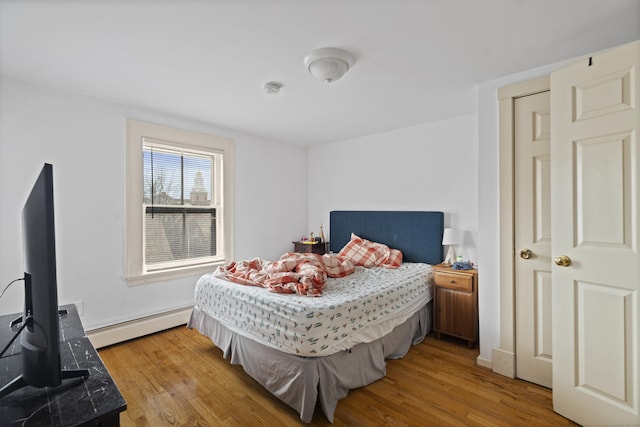 bedroom featuring wood finished floors and a baseboard radiator