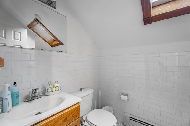 bathroom with toilet, vanity, lofted ceiling, baseboard heating, and tile walls