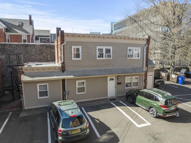 townhome / multi-family property featuring uncovered parking and a shingled roof