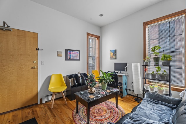 living area with a baseboard heating unit and wood finished floors