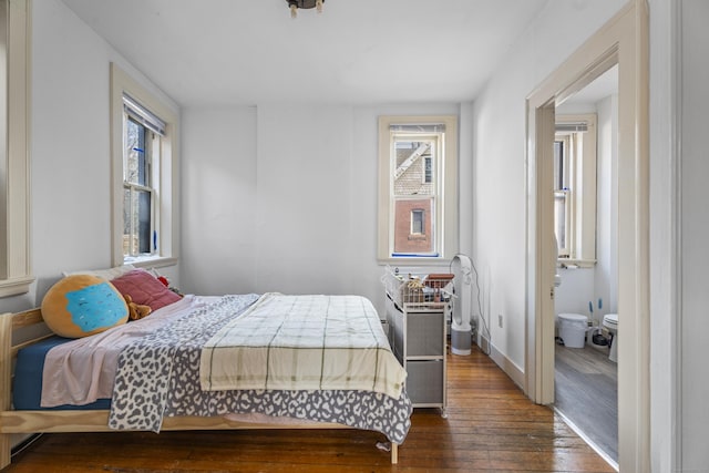 bedroom featuring hardwood / wood-style floors, multiple windows, baseboards, and ensuite bathroom