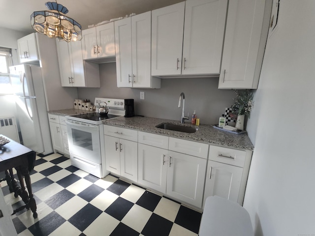 kitchen featuring white appliances, light floors, radiator heating unit, a sink, and white cabinets